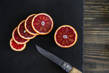 sliced sicilian or bloody oranges on a black slate background 