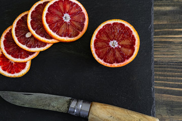 sliced sicilian or bloody oranges on a black slate background 