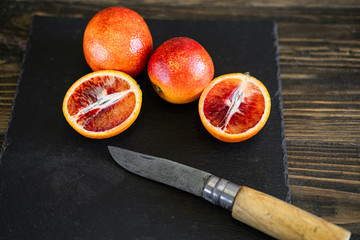 sliced sicilian or bloody oranges on a black slate background 