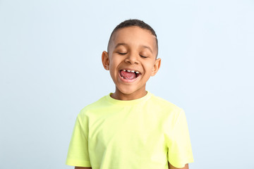 Happy smiling African-American boy on color background