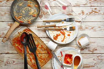 Dirty empty dishes and kitchenware on wooden background