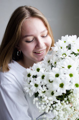 portrait of a young beautiful girl with blond hair and a short haircut with white flowers in her hands on a white background, the concept of beauty and health