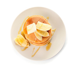 Tasty pancakes with honey, butter and banana on white background