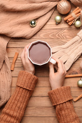 Fototapeta na wymiar Female hands with cup of hot chocolate on wooden background