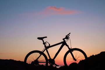 Naklejka na ściany i meble The silhouette of bike on the beach with purple sunset sky background