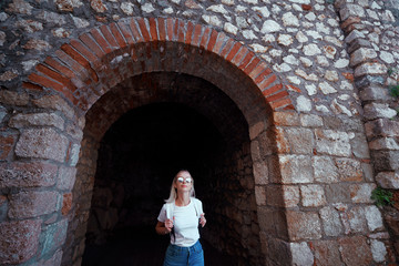 Fototapeta na wymiar Young traveling woman with rucksack walking in ancient fortress.