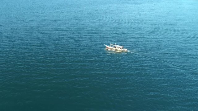 Drone view a traditional bangka boat floating in the open ocean on the sunset, Palawan, Philippines