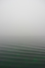 Waves rippling through water fading off into fog showing concept of loneliness and solitude