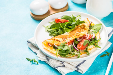 Omelette with green leaves at white plate.