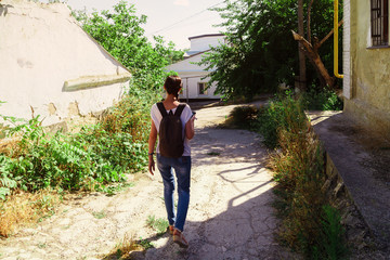Fototapeta na wymiar Girl with backpack walks down empty rural road