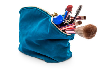 Makeup bag with various cosmetic accessories on white.