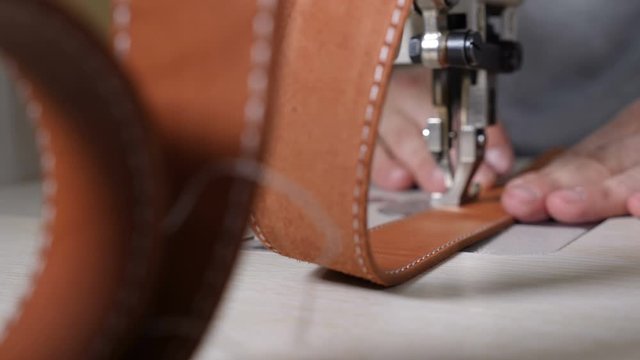 Close-up macro view of sewing machine in leather manufacture, sew leather for belt, bag or wallet. workshop by handmade artisan expert in manufacturing leather belts, manufacture. traditional