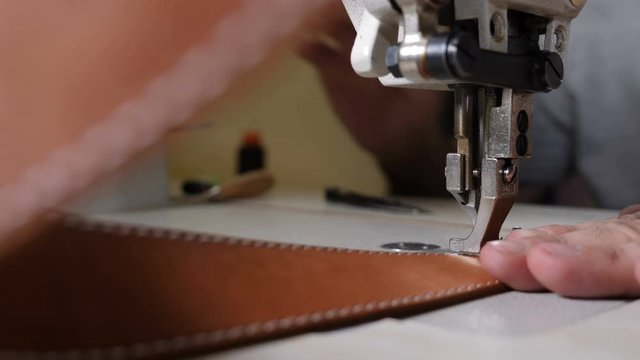 Close-up macro view of sewing machine in leather manufacture, sew leather for belt, bag or wallet. workshop by handmade artisan expert in manufacturing leather belts, manufacture. traditional