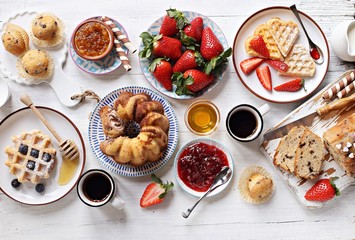 Festive family dessert table with various of cakes, waffles, sweets and fresh strawberry. Overhead view