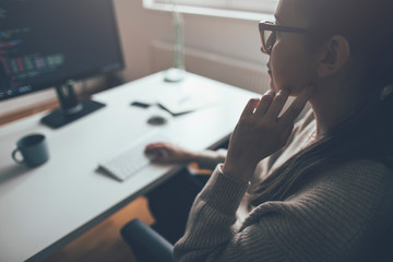 Side view of young woman working on computer from her home office