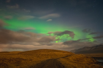Naklejka na ściany i meble Aurora Borealis in Iceland northern lights bright beams over hiking path