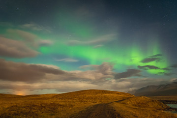 Aurora Borealis in Iceland northern lights bright beams rising green over hiking path