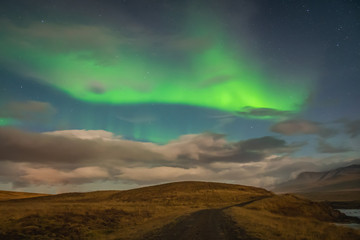 Aurora Borealis in Iceland northern lights bright beams rising in green beams over hiking path