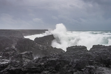 Fototapeta na wymiar Brimketill lava rock pool in Iceland huge wave hitting black basalt coast