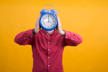 man holding alarm clock in his face