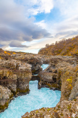 Hraunfossar series of waterfalls barnafoss turquoise water streaming down gorge in Iceland