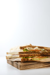 Dark and white bread sandwiches on a wooden board, isolated on white background