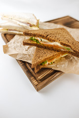 Dark and white bread sandwiches on a wooden board, isolated on white background