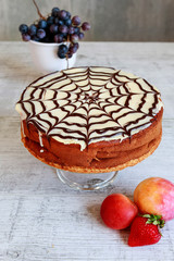 Halloween chocolate spider web cake and various fruits around.