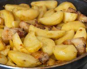 Fried potatoes with meat in a pan with spices cooked at home