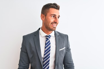 Young handsome business man wearing suit and tie over isolated background looking away to side with smile on face, natural expression. Laughing confident.