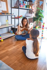 Beautiful teacher teaching  toddler  alphabet around lots of toys at kindergarten