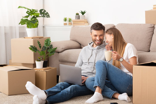 Happy couple sitting among moving boxes and having fun