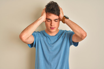 Teenager boy wearing casual t-shirt standing over isolated background suffering from headache...