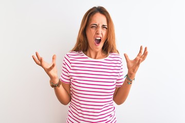 Young redhead woman wearing striped casual t-shirt stading over white isolated background crazy and...