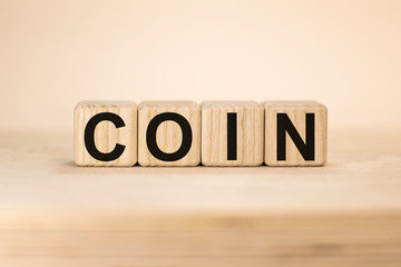 Word COIN on wooden cubes on yellow background