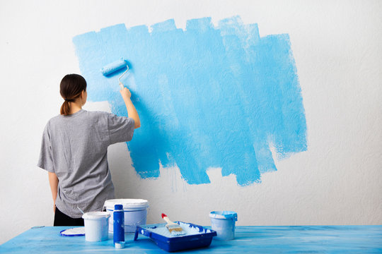 Woman Painting Interior Wall With Paint Roller