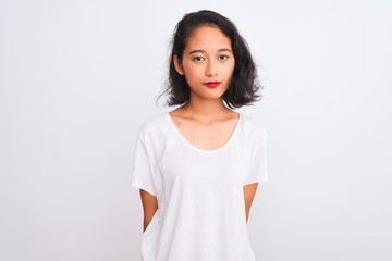 Young chinese woman wearing casual t-shirt standing over isolated white background with serious...