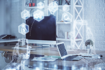 Computer on desktop in office with technology theme hologram. Multi exposure. Tech concept.