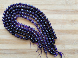 Amethyst crystal bead stands on wood background with copy space on the right side.
