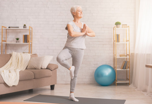 Senior Woman Doing Yoga Tree Pose At Home, Free Space