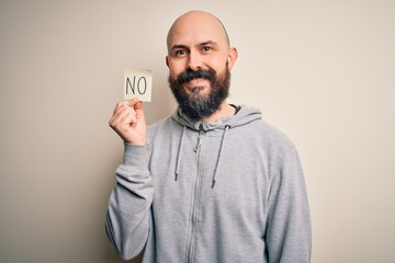 Handsome bald man with beard holding reminder paper with negative message with a happy face standing and smiling with a confident smile showing teeth