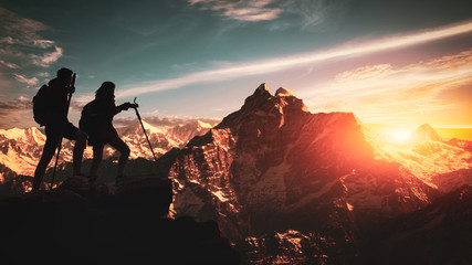 Young asian couple hikers climbing up on the peak of himalaya mountains. People helping each other hike up a mountain at sunrise. Giving a helping hand. Climbing ,Helps and team work concept - obrazy, fototapety, plakaty