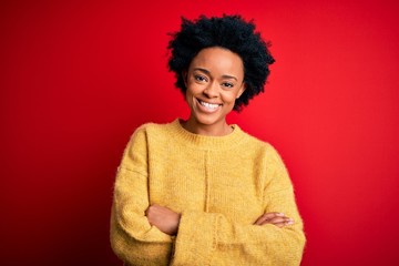 Young beautiful African American afro woman with curly hair wearing casual yellow sweater happy...