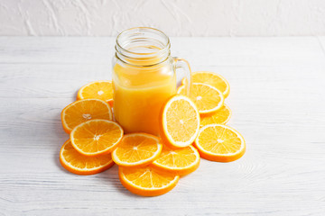 Fresh orange juice in glass glasses, orange slices on a light background. Bright fruit is delicious, refreshing and healthy