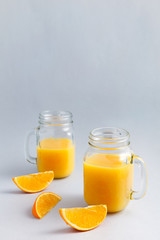 Fresh orange juice in glass glasses, orange slices on a light background. Bright fruit is delicious, refreshing and healthy