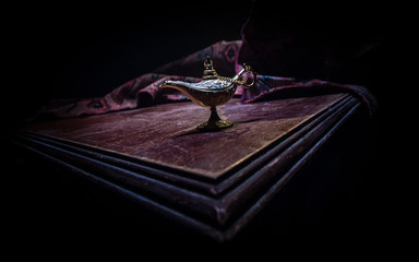 Lamp of wishes concept. Antique Aladdin arabian nights genie style oil lamp with soft light white...