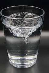 swirling spinning water in a glass with bubbles isolated on a black background