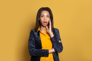 Shocked young pretty black girl against yellow background. Surprised American woman portrait