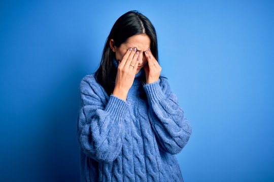 Young brunette woman with blue eyes wearing casual turtleneck sweater rubbing eyes for fatigue and headache, sleepy and tired expression. Vision problem
