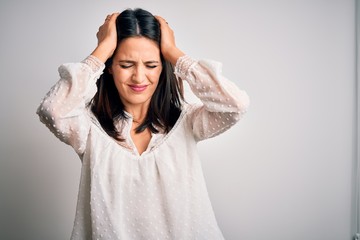 Young brunette woman with blue eyes wearing casual t-shirt over isolated white background suffering from headache desperate and stressed because pain and migraine. Hands on head.